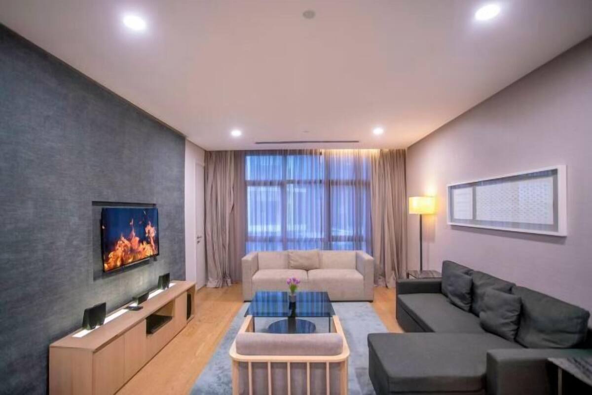 Een moderne woonkamer met een flatscreen televisie, een bank, een salontafel en een lamp.