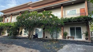 A two-story building with a flat roof, large windows, and a covered entrance area with potted plants. - Wilawan home (Koh Samui)