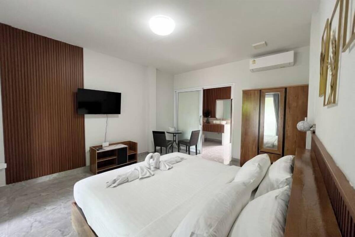 Une chambre d’hôtel moderne dotée d’un grand lit, d’un téléviseur à écran plat fixé au mur, d’un bureau avec des chaises et d’une armoire.