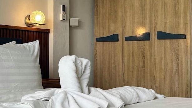 A hotel room with a wooden wardrobe, a bedside lamp, and a neatly made bed. - Wilawan home (Koh Samui)