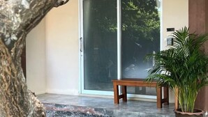 A sliding glass door leading to a room with a bench and a potted plant. - Wilawan home (Koh Samui)