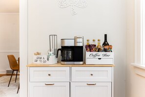 Eine Küchenzeile mit einer Keurig-Kaffeemaschine, einer Kaffeoecke und einem Schild mit der Aufschrift 'Kaffee zum Mitnehmen!'.