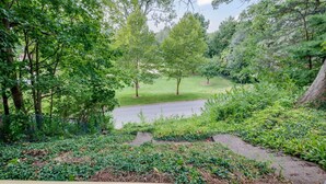 Un jardin luxuriant avec un chemin pavé menant à une zone herbeuse.