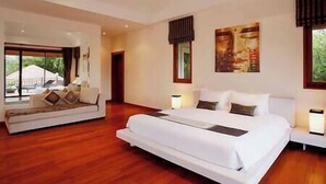A modern bedroom with a large bed, a sofa, and a view of the outdoors. - Laguna Waters - Lake View Villa, 5 Bedrooms (Bang Tao)