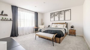 A bedroom with a bed, bedside tables, a desk, and a chair.