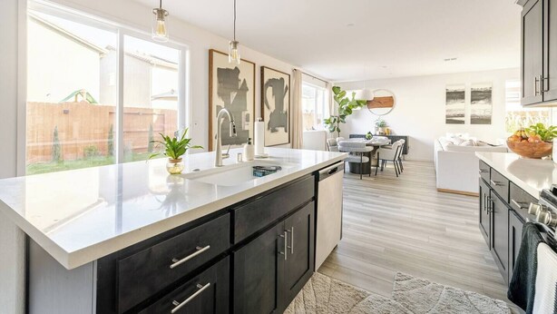 A modern kitchen with a large island, dark cabinetry, and pendant lighting.
