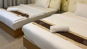 Habitación de hotel con dos camas, cortinas color beige, una pared decorada con cestas tejidas y suelo de madera.