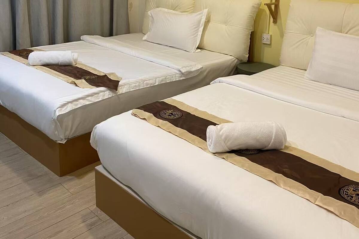 Habitación de hotel con dos camas, cortinas color beige, una pared decorada con cestas tejidas y suelo de madera.