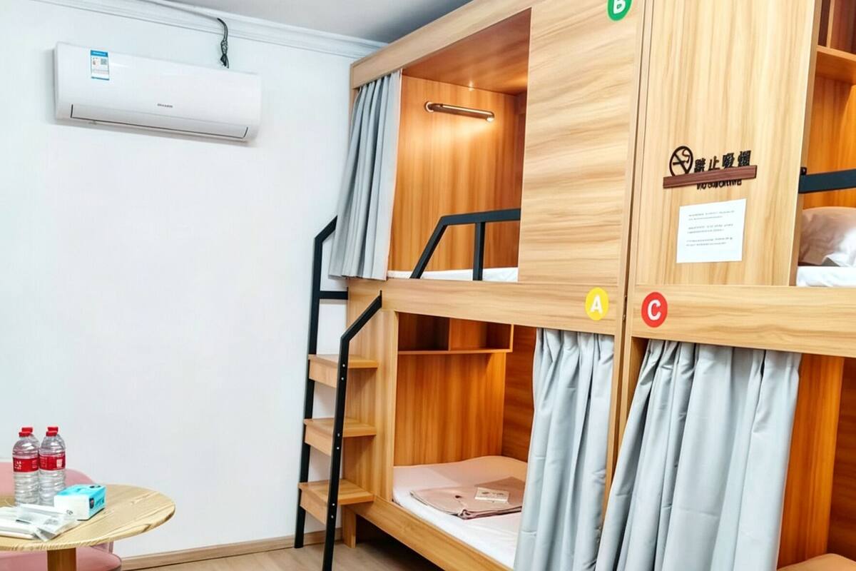 Habitación con literas, escritorio, silla y una mesita con botellas de agua.