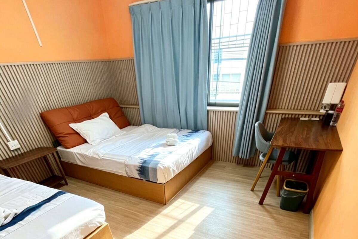 Habitación de hotel con dos camas, un escritorio, una silla y un radiador.