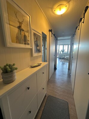 A hallway with a white dresser, a framed deer head, a potted plant, and a mirror.