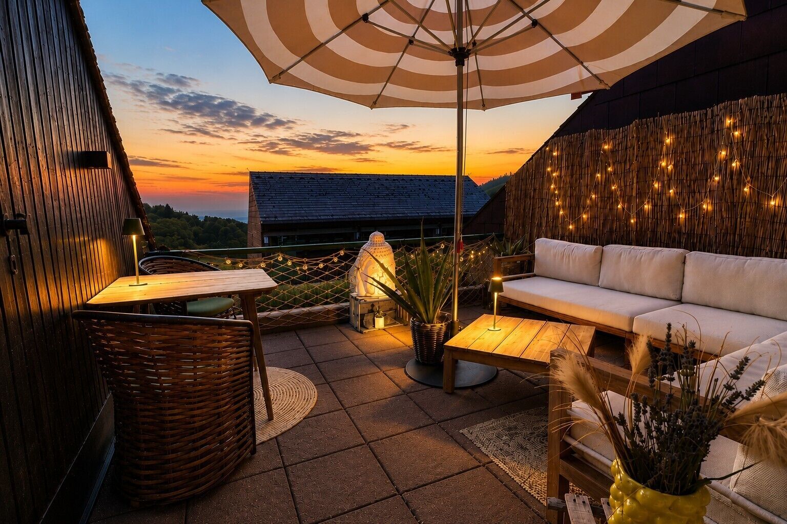 Un patio al aire libre con un sofá, mesas y una sombrilla, con vistas a un hermoso atardecer.