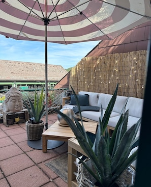 A patio area with a sofa, a Buddha statue, and potted plants.
