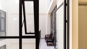 A corridor with a glass door, a bench, and a view of a building outside.