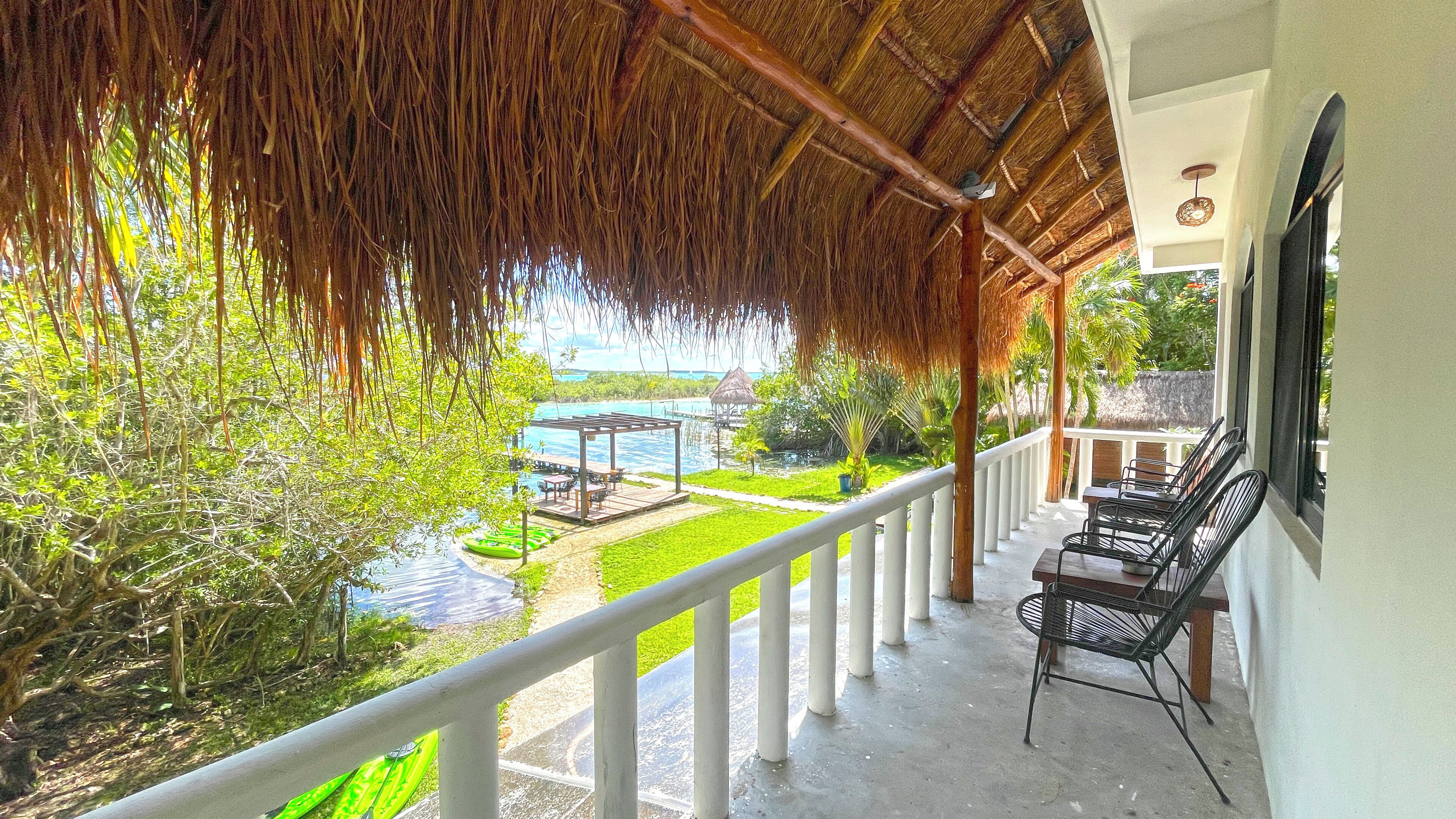 A covered outdoor area with a view of a pool and greenery.