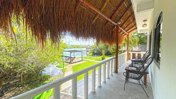 A covered outdoor area with a view of a pool and greenery.