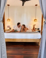 A bed with a wooden frame, two hanging lamps, and a poster on the wall.
