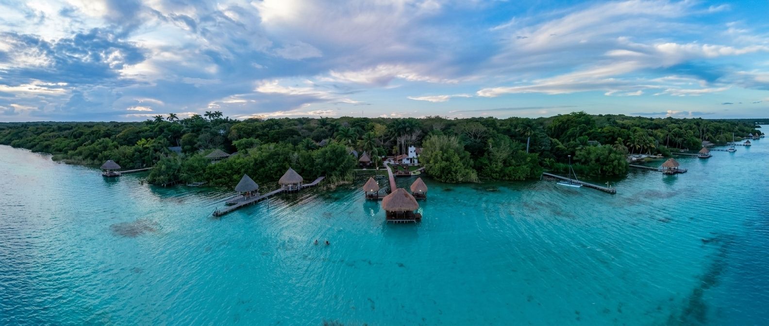 Una vista aerea di un'isola tropicale con bungalow sull'acqua collegati da passerelle.