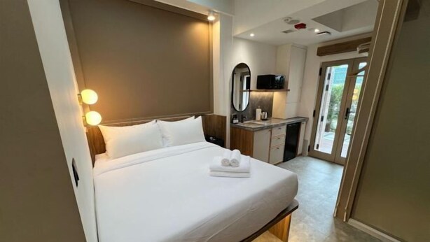 Une chambre d’hôtel avec un lit, des lampes de chevet, un petit bureau avec un miroir et une vue sur l’extérieur.