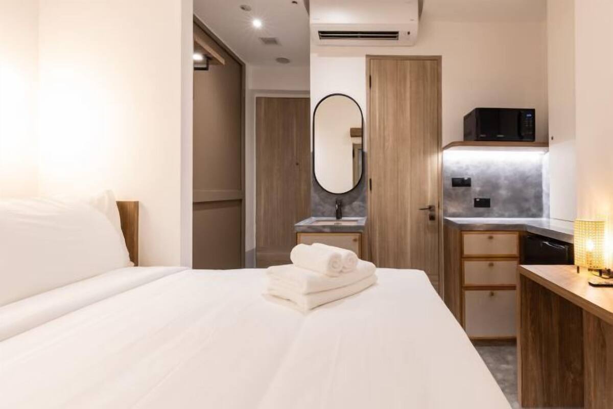 A hotel room with a bed, a bathroom with a mirror, a microwave, and a sink.