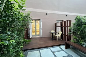 A courtyard with a wooden deck, a small table with chairs, and a door leading to a room. - Heritage Collection on Victoria - Mobile App Check-In (Singapore)