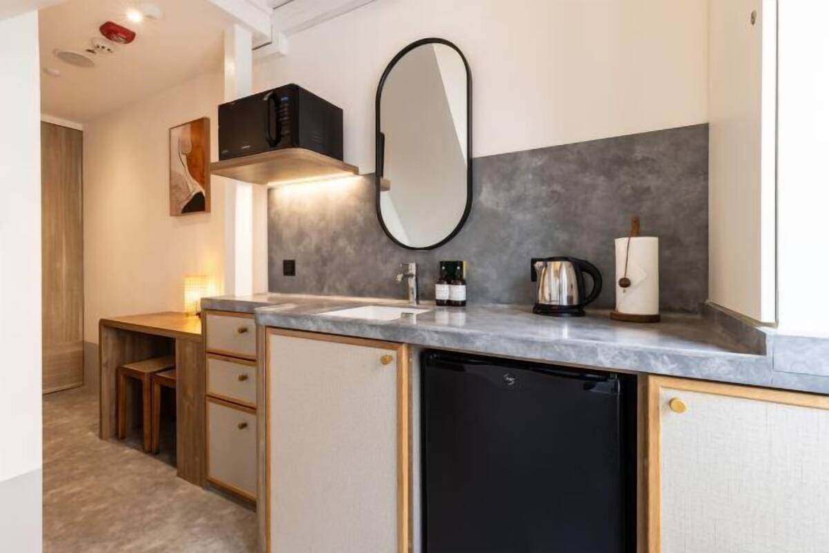 A compact kitchen with a built-in dishwasher, a coffee maker, and a kettle on the countertop.
