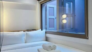 Una habitación de hotel con una cama, un ventanal con vistas al exterior y una puerta.