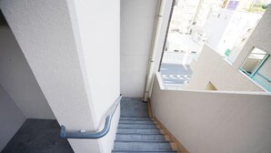 A staircase with a handrail, leading to an outdoor area with a view of buildings. - Chuan House Kuromon (Osaka)