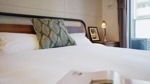 A neatly made bed with white linens, a green patterned pillow, and a framed picture on the nightstand beside it. - Chuan House Kuromon (Osaka)