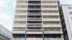 A multi-story building with balconies, a sign with Chinese characters, and a modern architectural design. - Chuan House Kuromon (Osaka)