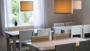 A dining area with a table and chairs, a window with curtains, and a clock on the wall. - 2 Person Holiday Park Home in 82011 (Vallsta)