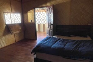 Une pièce comprenant un lit, un plancher en bois, une fenêtre donnant sur un paysage agréable et une porte menant à une autre pièce.