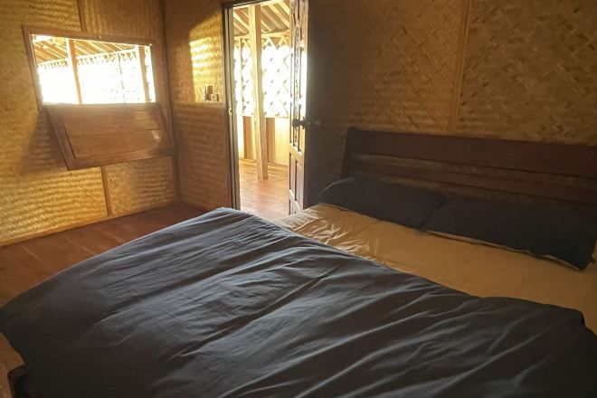 A bedroom with a bed, a window, and a door leading to another room.