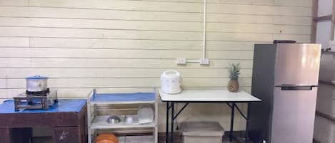 A compact kitchen area with a refrigerator, a small table, and a coffee maker.