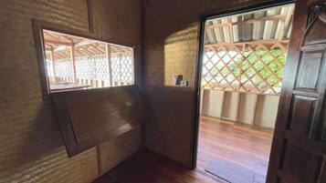 Une pièce de style japonais traditionnel, avec un sol recouvert de tatamis, une porte coulissante et une fenêtre ornée d’un treillis.