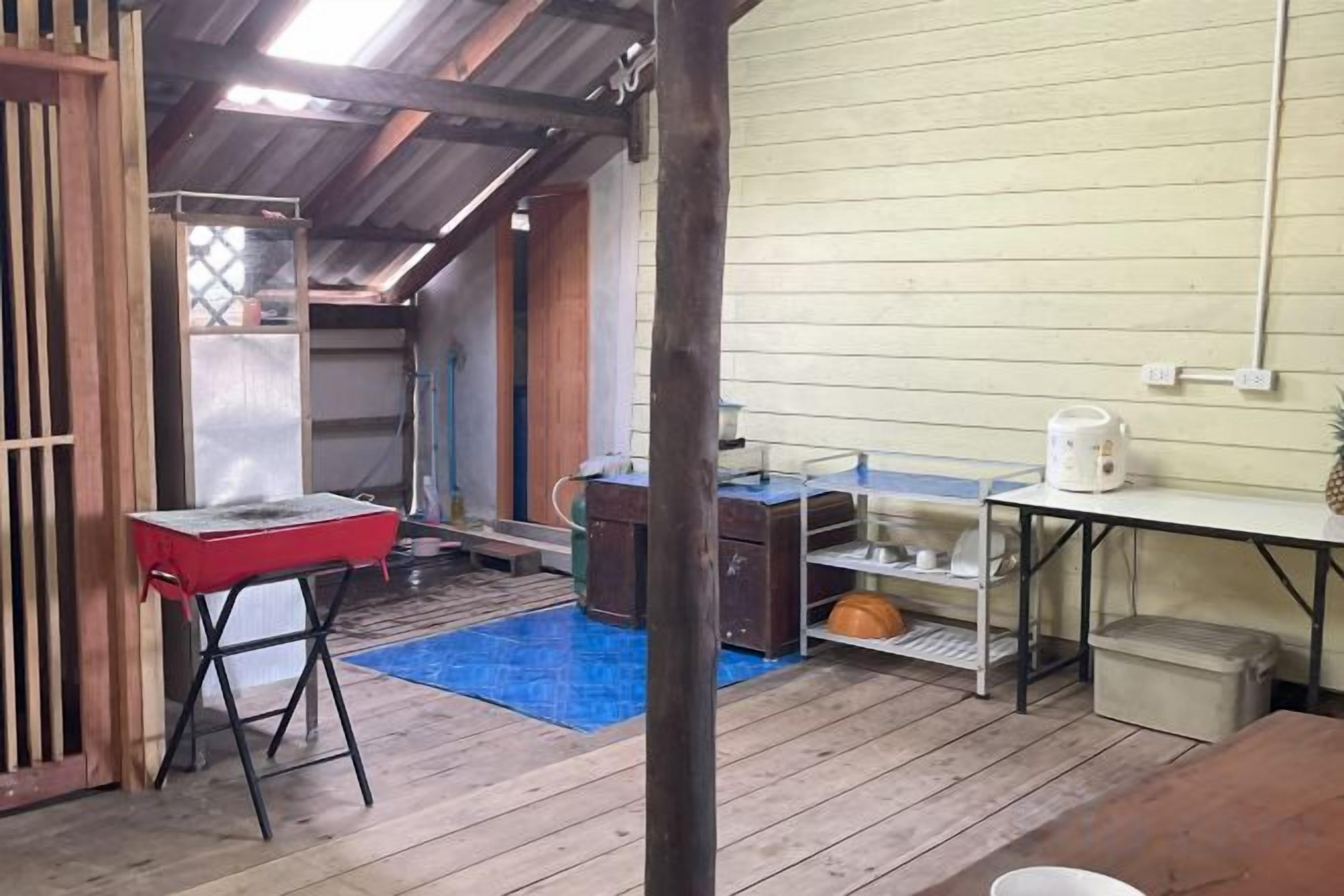 Une pièce avec un plancher en bois, une table rouge, un tapis bleu, un évier blanc et un meuble en bois.