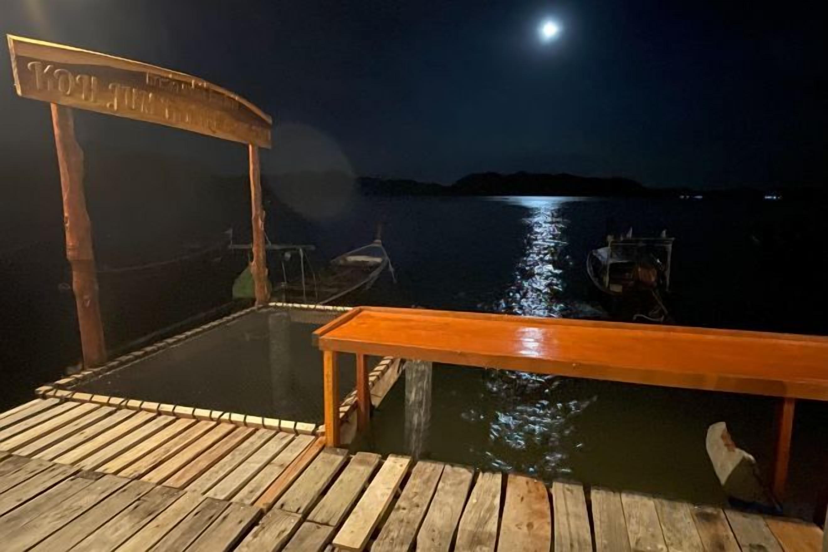 A wooden dock with a bench and a boat moored in the water.