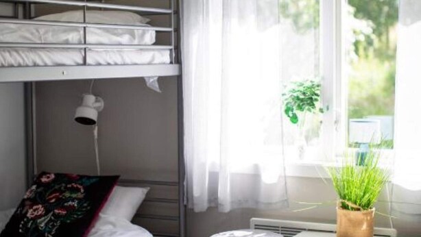 A bunk bed with a pillow, a small table with a plant, and a window with curtains. - 4 Person Holiday Park Home in 82011 (Vallsta)
