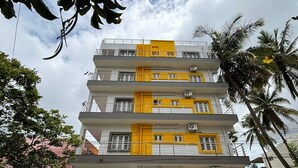 A multi-story building with yellow and white exterior walls, balconies, and air conditioning units. - Surya-Atharva Suites (Mysore)