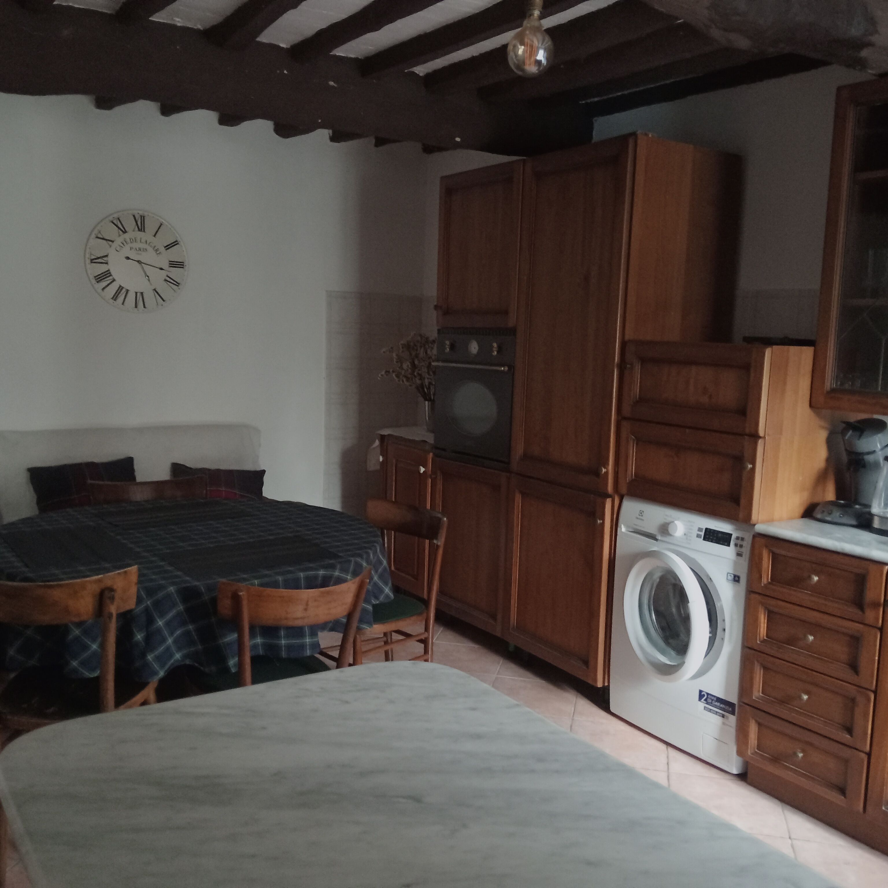 Une chambre à coucher avec un lit, une armoire en bois, un lave-linge et une horloge au mur.