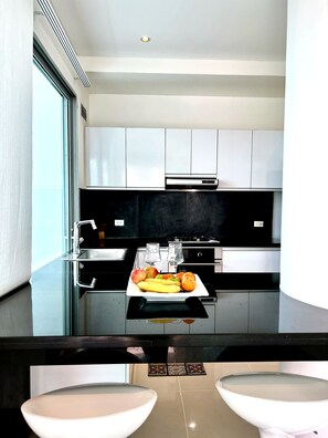 A modern kitchen with a central island, stainless steel appliances, and a fruit bowl.