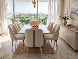 A dining area with a table set for six, a view of the cityscape, and a modern interior design.