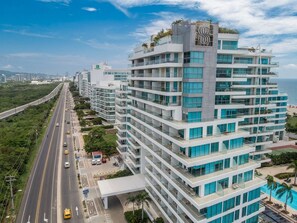 A multi-story hotel with balconies, a swimming pool, and a view of the ocean.