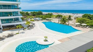Un complexe hôtelier doté d’une grande piscine, de chaises longues et offrant une vue sur la plage.