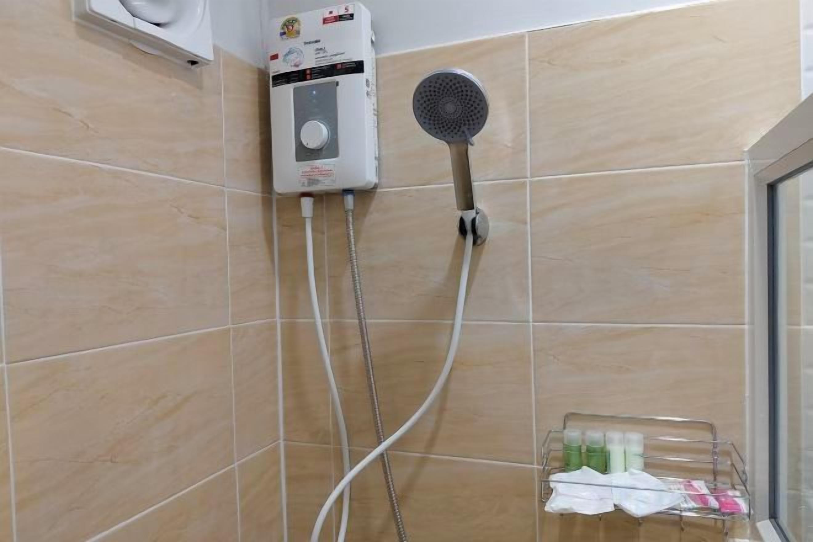 A bathroom with a shower, a handheld showerhead, and a wall-mounted control unit.