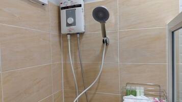 A bathroom with a shower, a handheld showerhead, and a wall-mounted control unit.