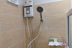 A bathroom with a shower, a handheld showerhead, and a wall-mounted control unit. - AT resort (Lam Thamenchai)