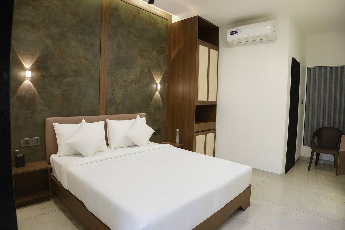 Hotellihuone, jossa on suuri sänky, yöpöytä, tuoli ja sisäänrakennettu vaatekaappi.