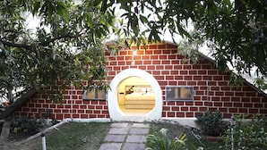 Un bâtiment en briques doté d’une fenêtre circulaire et dont on peut apercevoir un lit à l’intérieur.