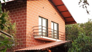 Un bâtiment à deux étages, construit en briques, doté d’un balcon, d’un escalier et d’un petit jardin.